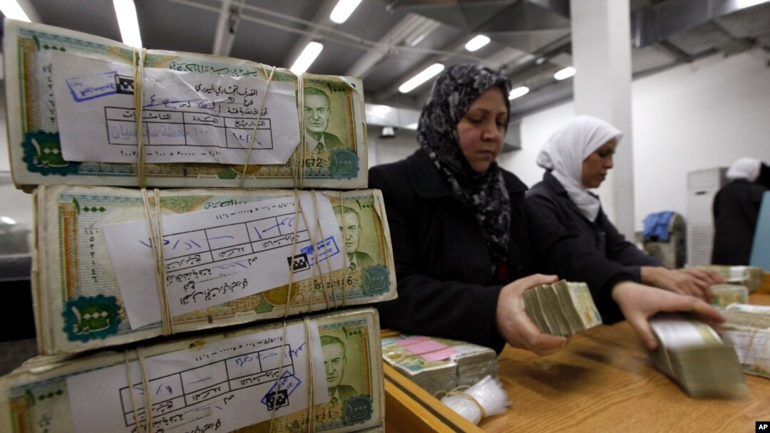 FILE - In this January 13, 2010 file photo, Syrian employees stack packets of Syrian currency in the Central Syrian Bank in, Damascus, Syria.