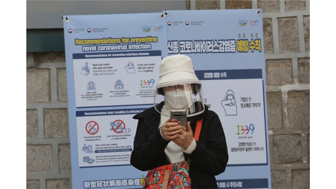 A woman wearing a face mask watches her smartphone in Seoul, South Korea, Saturday, March 21, 2020.