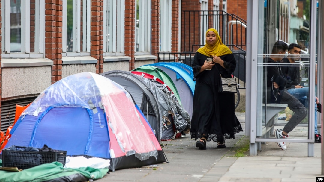 A woman walks past tents at a makeshift refugee camp outside the Irish Governments International Protection Office, in Dublin, Ireland, on June 12, 2023. (Photo by PAUL FAITH / AFP)