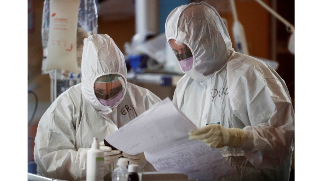 Medical workers in protective suits check a document as they treat patients suffering with coronavirus disease (COVID-19) in an intensive care unit at the Casalpalocco hospital in Rome, March 24, 2020.