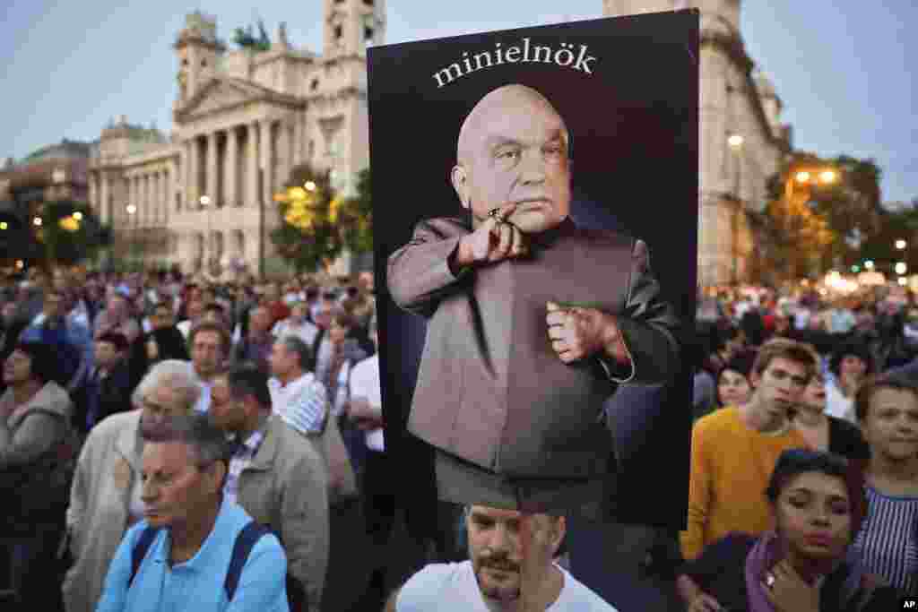 A man holds a banner depicting Hungarian Premier Viktor Orban, the reads "mini-prime minister" during a protest against Orban's policies regarding migrants in Budapest, Hungary, Sept. 30, 2016.