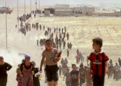 FILE - Displaced people from the Yazidi sect, fleeing violence from forces loyal to Islamic State militants in Sinjar, walk toward the Syrian border on the outskirts of Sinjar mountain.