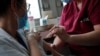 A member of the medical staff administers the Oxford-AstraZeneca COVID-19 vaccine to a colleague at the Foch hospital in Suresnes, near Paris, France, Feb. 8, 2021. 