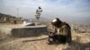 Un hombre lee el Corán junto a la tumba de un familiar en un cementerio en las afueras de Kabul, Afganistán, el 14 de enero de 2021.