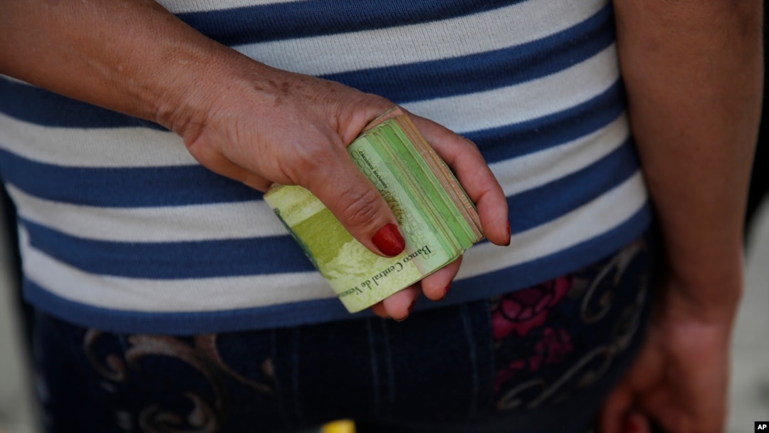 En esta fotografía de archivo del 7 de febrero de 2018, una mujer sostiene un gran fajo de billetes para pagar el pasaje del autobús en Caracas, Venezuela. Febrero 7, 2018. Foto: AP.
