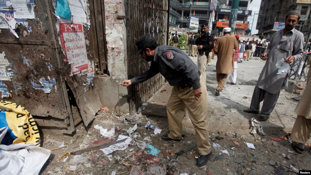 A police officer collects evidence from the site of a bomb blast on University Road in Peshawar, Apr. 29, 2013. 