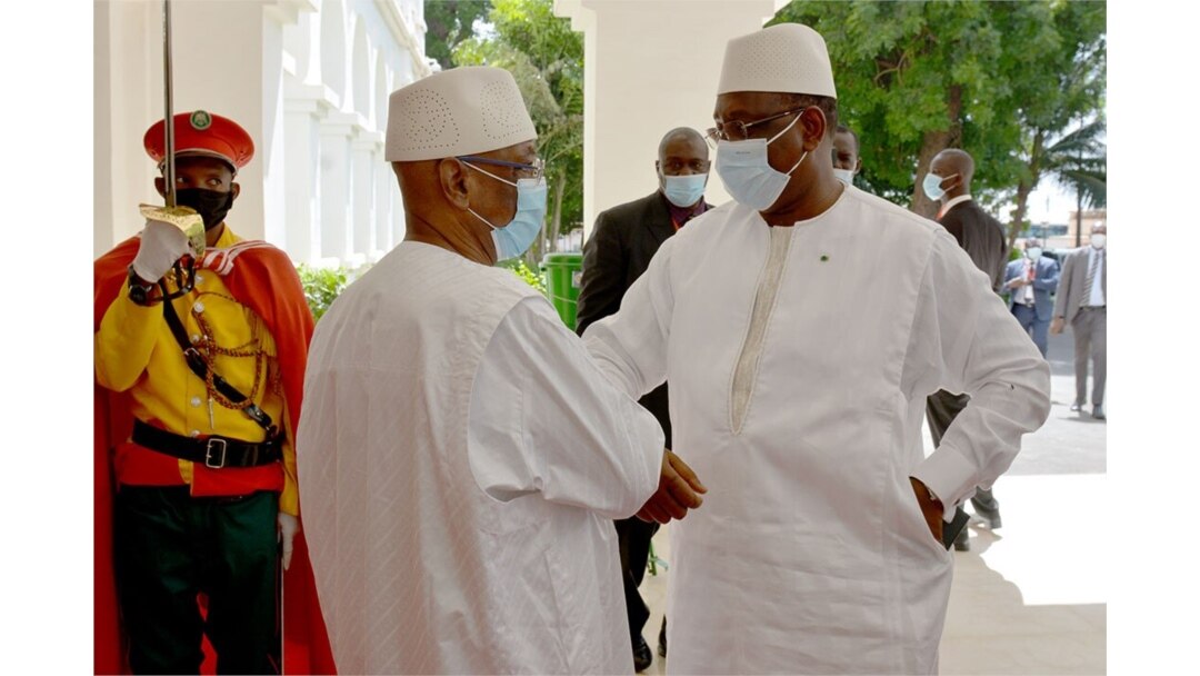 Mali's President Ibrahim Boubacar Keita, right, and Senegal's President Macky Sall exchange greetings outside a Bamako hotel, July 23, 2020. A handful of West African leaders met to discuss Mali's political turmoil over Keita. (K. Traore/VOA)