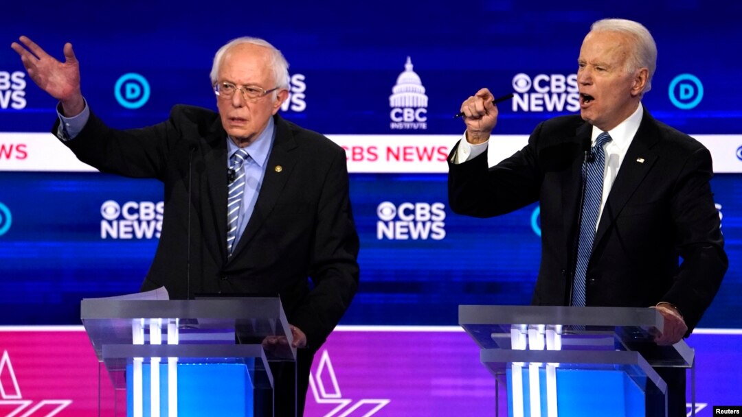 FILE - Democratic 2020 U.S. presidential candidates Senator Bernie Sanders (L) and former Vice President Joe Biden talk at the presidential debate at the Gaillard Center in Charleston, South Carolina, Feb. 25, 2020.