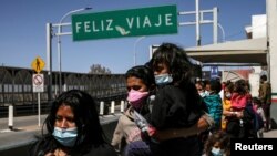 Migrantes de América Central en busca de asilo, que fueron transportados en avión desde Brownsville a El Paso, Texas, y ahí deportados de Estados Unidos, cruzan el puente fronterizo internacional Paso del Norte, en Ciudad Juárez, México, 23 de marzo 2021.