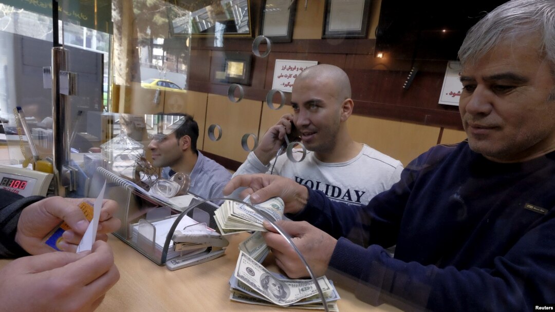 FILE - A currency exchange dealer counts U.S. currency at his shop in a shopping center in northern Tehran, Iran, Jan. 17, 2016. Iran's troubled currency fell to a new low against the U.S. dollar on Saturday.