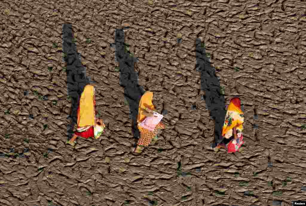 Women walk on the muddy banks of the Ganges river after taking a holy dip, in Allahabad, India.