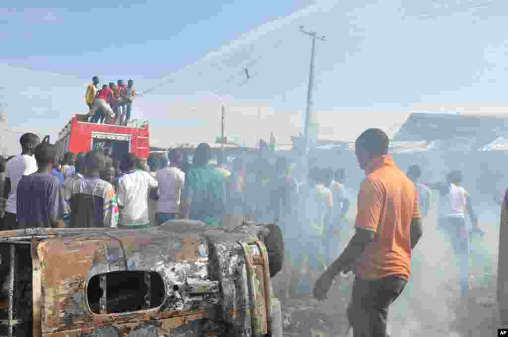 Mutane sun taru kusa da inda bam ya tashi cikin mota a kasuwar "Monday Market" ta Maiduguri, talata 1 Yuli, 2014. Mutane da dama sun mutu, akasarinsu mata tsoffi da almajirai dake bara.