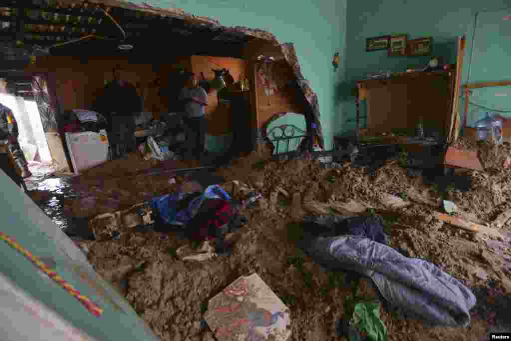 People stand in a house flooded by mud after a mountain landslide in Altotonga in Veracruz state, along Mexico's Gulf coast, Sept. 16, 2013. 