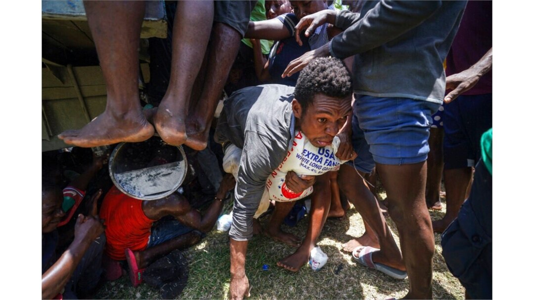 A resident crawls away with a donated bag of rice after residents overtook a truck loaded with earthquake relief supplies, in Vye Terre, Haiti, Aug. 20, 2021.
