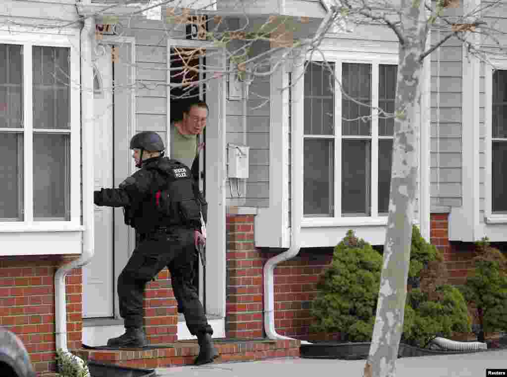 A man looks out of his door as a SWAT team member knocks on his neighbors door as they search for the remaining suspect in the Boston Marathon bombings in Watertown, April 19, 2013.