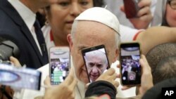 Pope Francis is framed by cellphones as he arrives for his weekly general audience, in the Pope Paul VI hall, at the Vatican, Wednesday, Jan. 9, 2019. 
