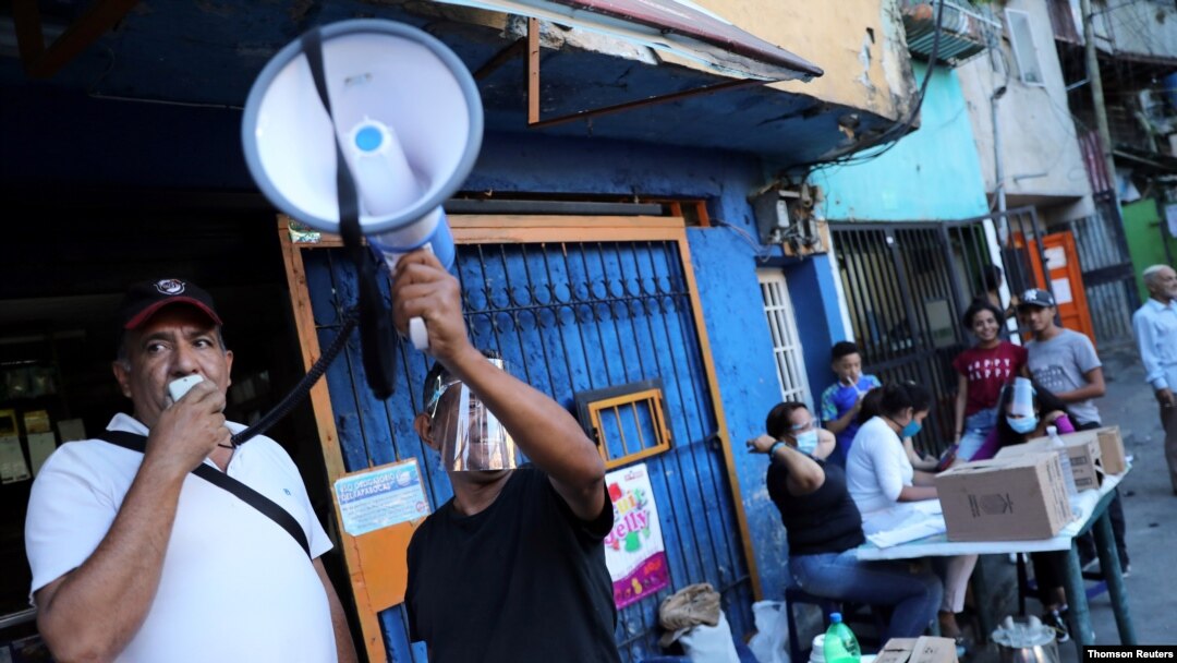 Voluntarios utilizan un megáfono cerca de un centro de votación para la consulta popular destinada a rechazar las elecciones parlamentarias del 6 de diciembre en el barrio de bajos ingresos de La Cruz en Caracas. Diciembre 12, 2020.
