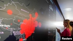 A reporter stands in front of a coronavirus global map during a tour of the "secretary's operation center" as part of a coronavirus task force meeting at the Department of Health and Human Services in Washington, Feb. 27, 2020.