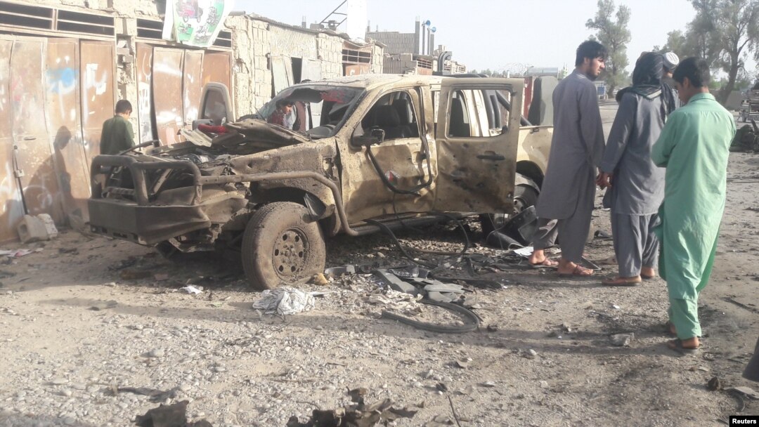Residents look at an Army vehicle which was damaged during battle between Afghan security forces and Taliban in Farah province, Afghanistan, May 16, 2018.