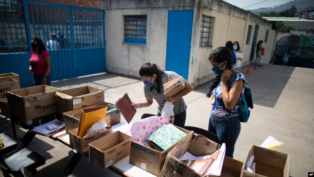 Una maestra revisa una lista mientras sostiene tareas entregadas por los padres que no tienen acceso a Internet, en la escuela Fe y Alegría en Caracas, el 12 de mayo de 2020. [Foto: AP]
