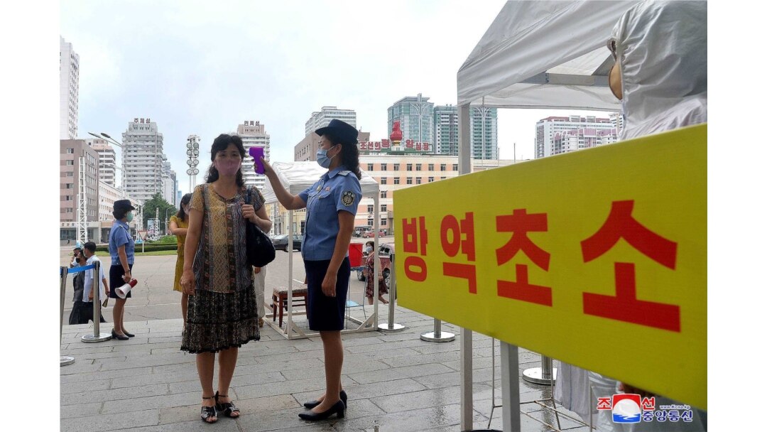 지난 8월 북한 평양역 입구에서 역무원이 신종 코로나바이러스 방역을 위해 승객들의 체온을 재고 있다.