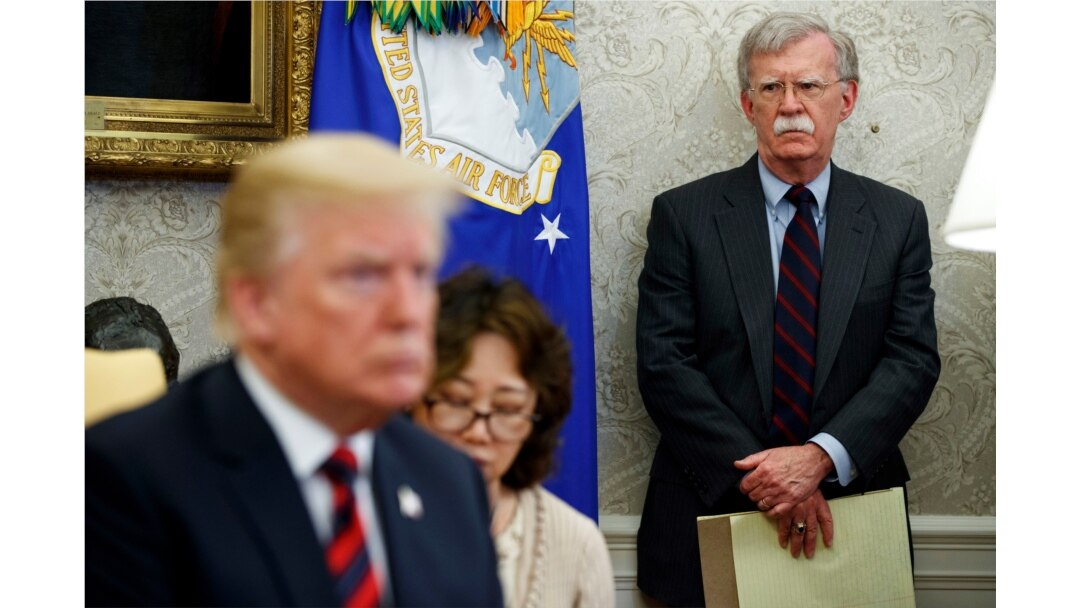 FILE - U.S. President Donald Trump, left, conducts a meeting in the Oval Office of the White House in Washington, May 22, 2018, as then-National Security Adviser John Bolton, right, looks on.
