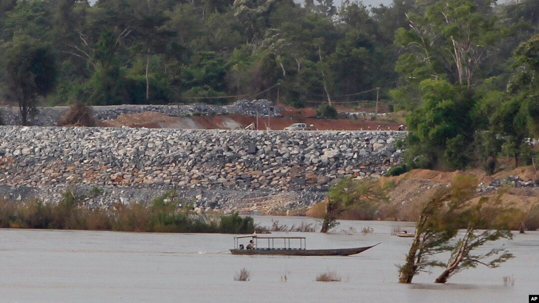 FILE - A fishing boat passes near a construction site of the Don Sahong dam, near the Cambodia-Laos border, June 20, 2016.