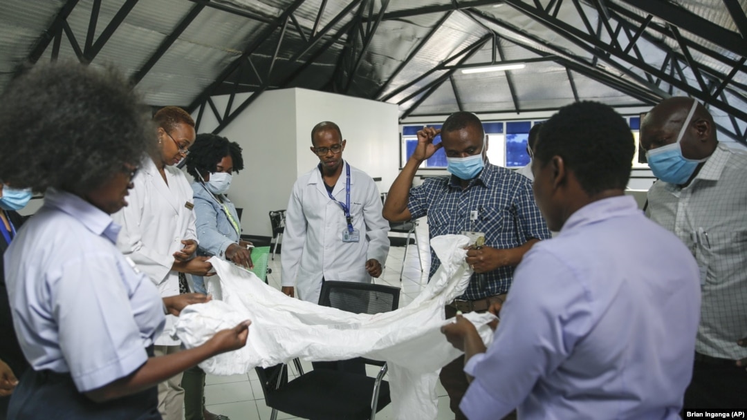 A health inspection officer shows doctors how to use protective equipment before they head to a ward at Mbagathi hospital for patients under quarantine and confirmed cases with the new coronavirus, at Kenyatta National Hospital in Nairobi, Kenya Thursday,