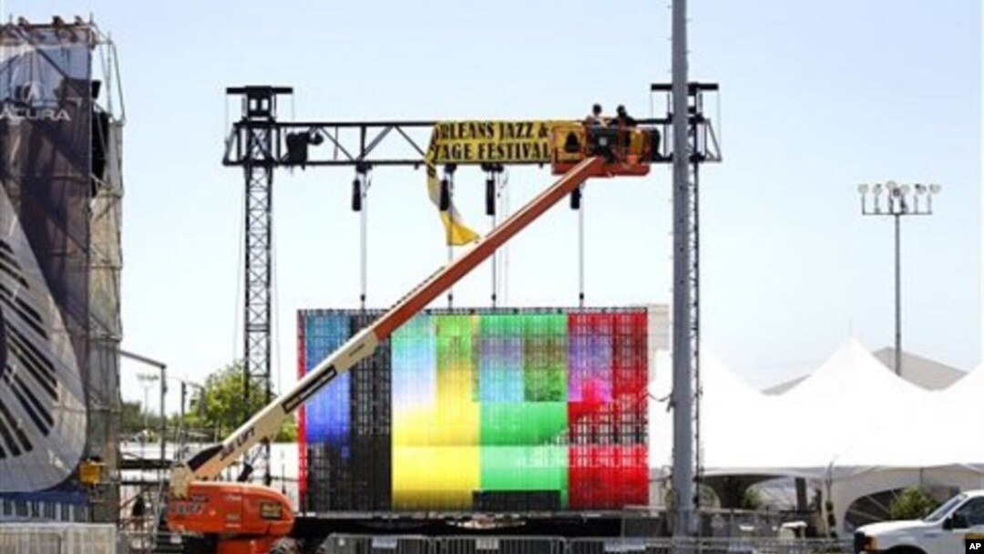 Workers hang signs in preparation for the New Orleans Jazz and Heritage Festival in New Orleans, April 28, 2011