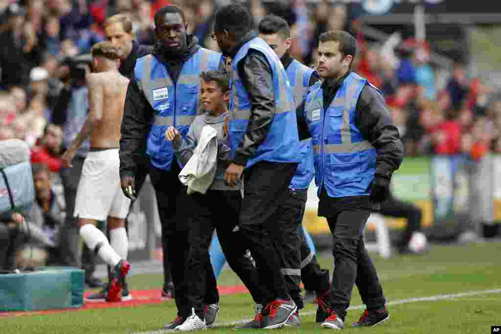 Security guards escort a crying boy who is holding the shirt PSG's Neymar, rear left, gave him after he ran onto the pitch at the end of the French League One soccer match between Rennes and Paris-Saint-Germain at Roazhon Park stadium in Rennes, western France.
