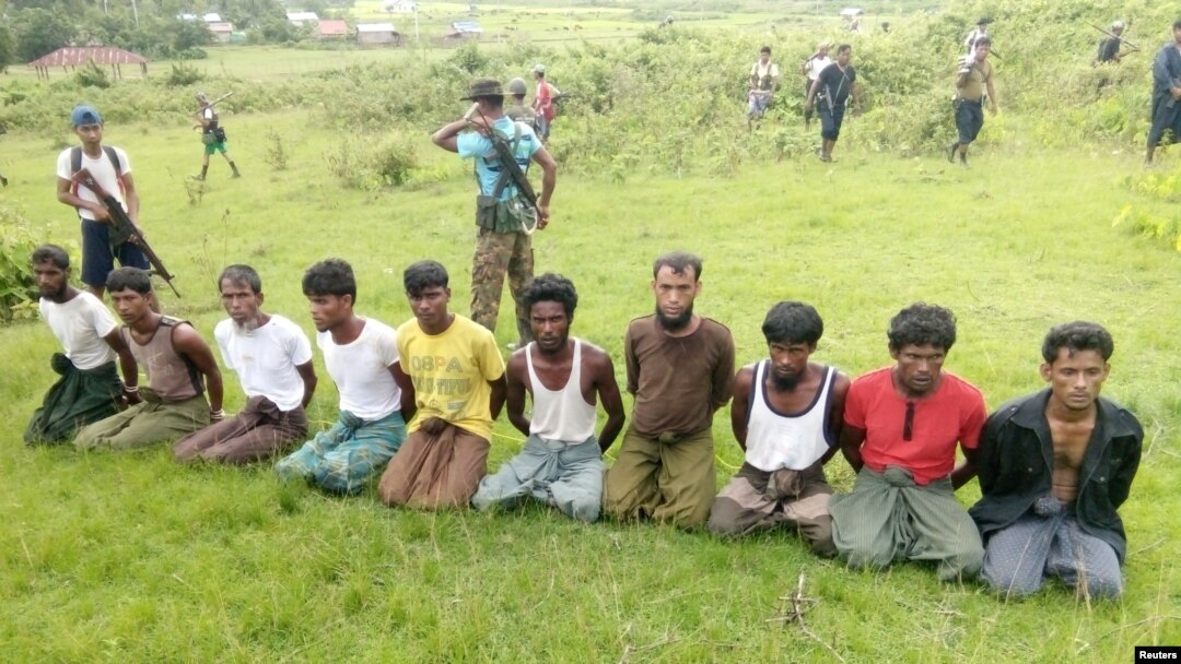 FILE - Ten Rohingya Muslim men with their hands bound kneel as members of the Myanmar security forces stand guard in Inn Din village, Sept. 2, 2017. 