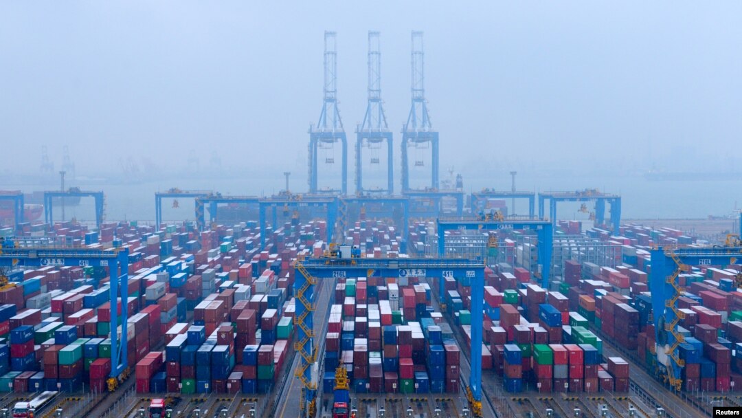 FILE - Containers and trucks are seen on a snowy day at an automated container terminal in Qingdao port, Shandong province, China, Dec. 10, 2018. 