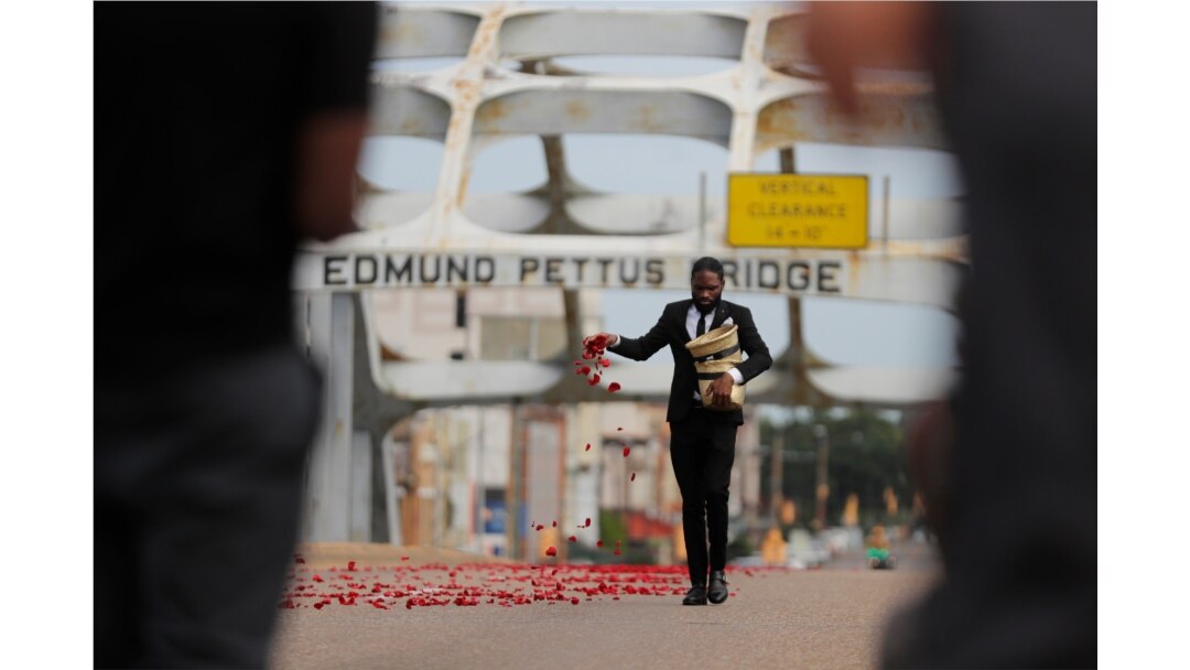 Un hombre riega pétalos en el puente Edmund Pettus antes de que el ataúd del legislador John Lewis fuera llevado por el puente en una procesión en su honor, el domingo 26 de julio de 2020.
