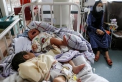 A woman sits next to newborn babies who lost their mothers following a suicide attack in a maternity hospital, in Kabul, May 13, 2020.