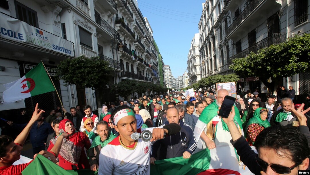 Demonstrators carry national flags as they march, a year since the start of weekly protests calling for a complete overhaul of the ruling elite, an end to corruption and the army's withdrawal from politics, in Algiers, Algeria, Feb. 14, 2020.