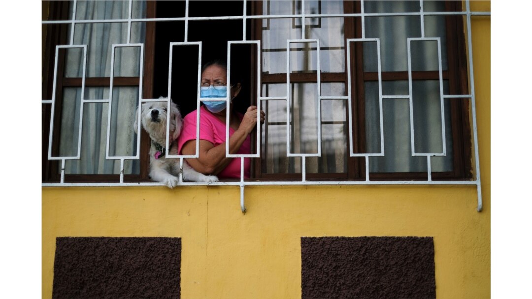 Un residente observa a los trabajadores sanitarios del municipio yendo de casa en casa, mientras realizan un seguimiento de contactos en medio de la pandemia, en Soyapango, El Salvador, el 3 de julio de 2020.
