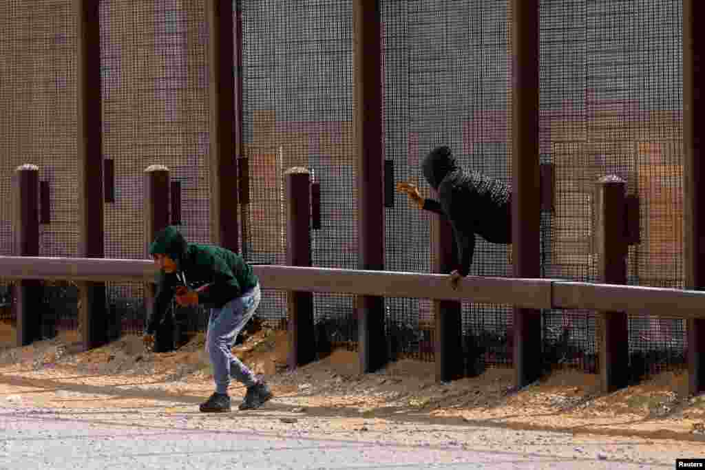 Migrants try to enter the United States undetected, through a hole in a section of the U.S.-Mexico border wall, in Sunland Park, New Mexico, Jan. 28, 2025.