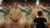 FILE - A man uses his mobile phone to take photos of a poster for the now delayed film "PM Narendra Modi" in Mumbai, India, Jan. 7, 2019.