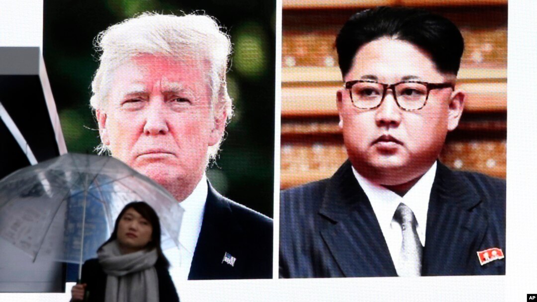 A woman walks by a huge screen showing U.S. President Donald Trump, left, and North Korea's leader Kim Jong Un, in Tokyo, Friday, March 9, 2018. After a year of threats and insults, Trump accepted an invitation to meet with Kim for talks about the North’s nuclear program. (AP Photo/Koji Sasahara)
