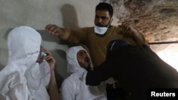 FILE - A man breathes through an oxygen mask as another one receives treatments, after what rescue workers described as a suspected gas attack in the town of Khan Sheikhoun in rebel-held Idlib, Syria, April 4, 2017. 