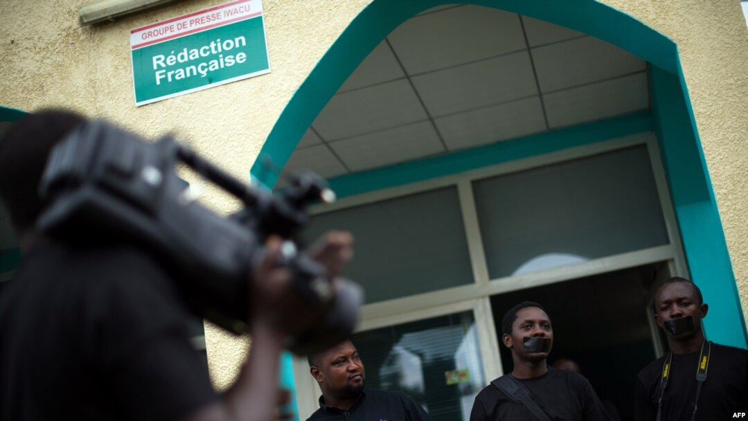 FILE - People with black tape covering their mouths attend a press conference of local journalists to mark World Press Freedom Day at the offices of the Iwacu media group in Bujumbura, Burundi, May 3, 2015. 